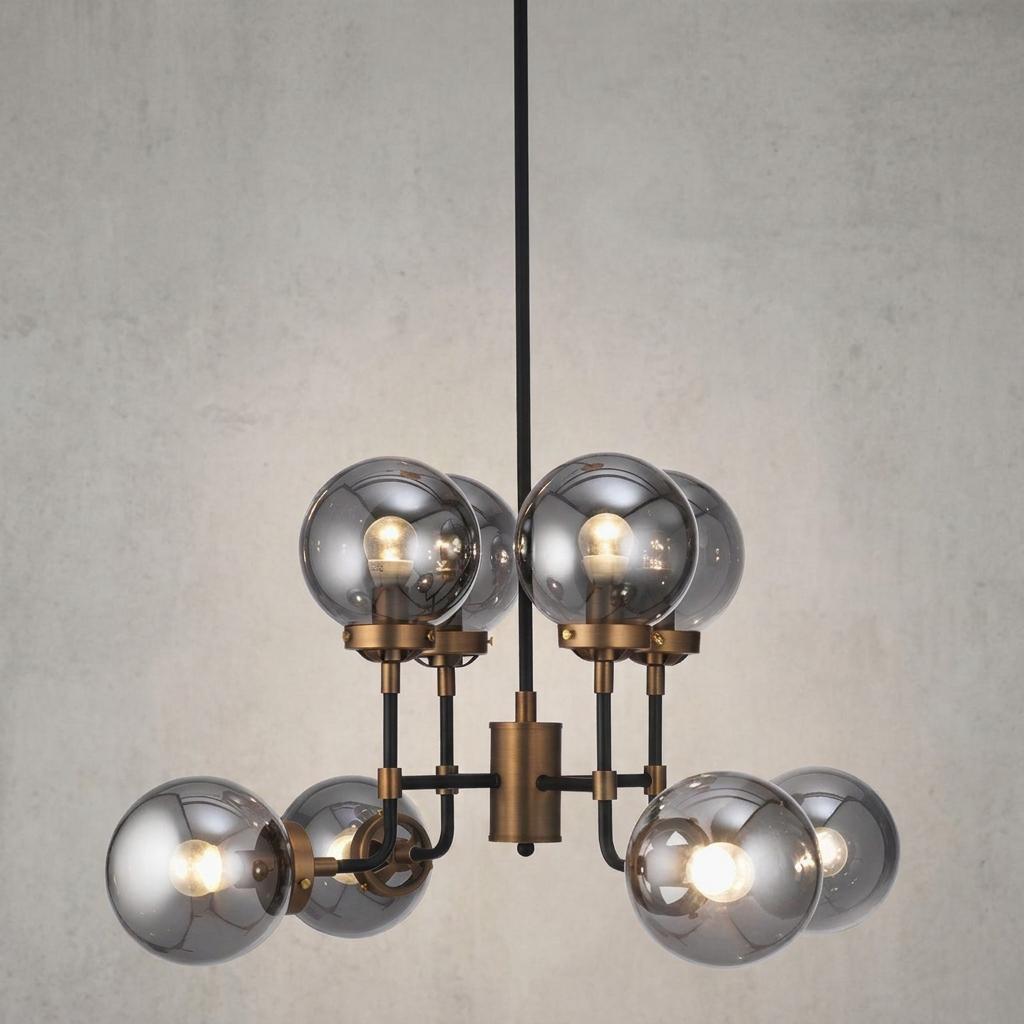 Modern gold and black chandelier with eight smoked glass globe shades illuminated against a grey wall.