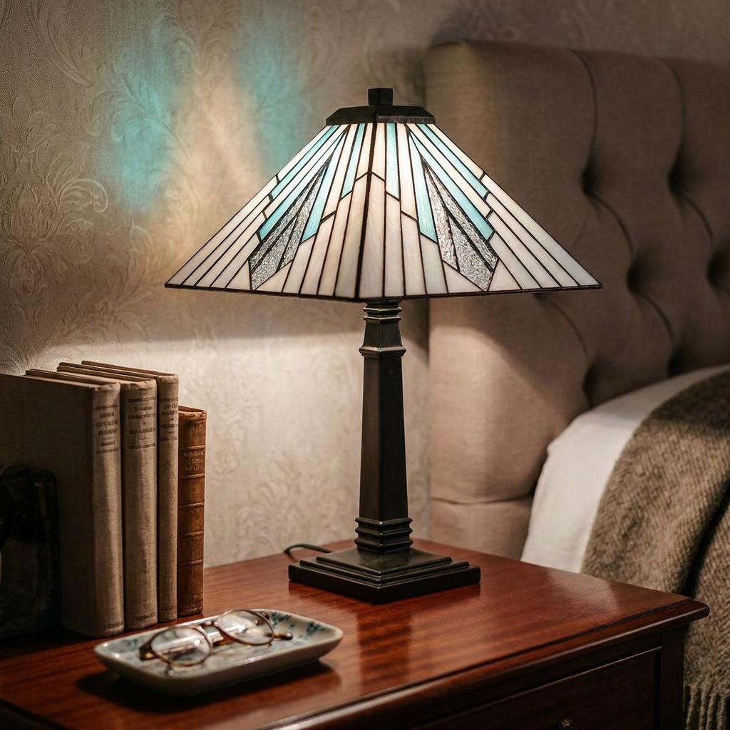 Art Deco Tiffany table lamp with a geometric glass shade on a wooden nightstand in a bedroom setting.