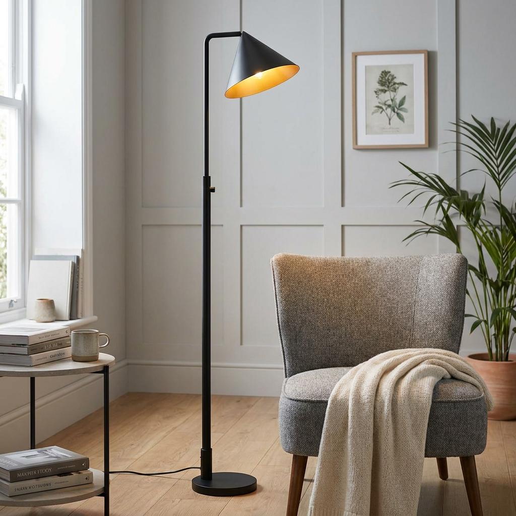 Alora Mood Remyck Black Floor Lamp with a gold interior shade standing next to a grey armchair in a cozy room.