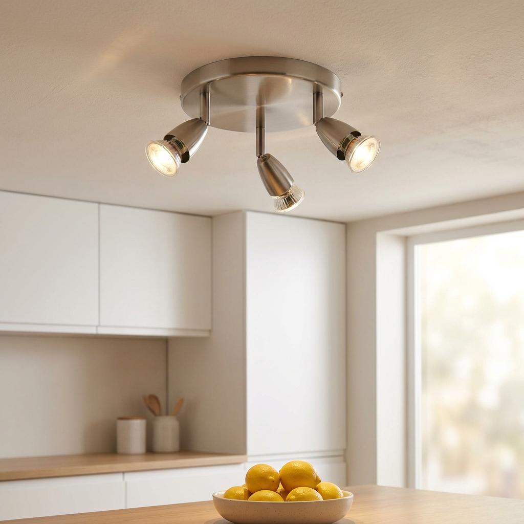 Three-light satin chrome spotlight fixture mounted on a kitchen ceiling above white cabinets.