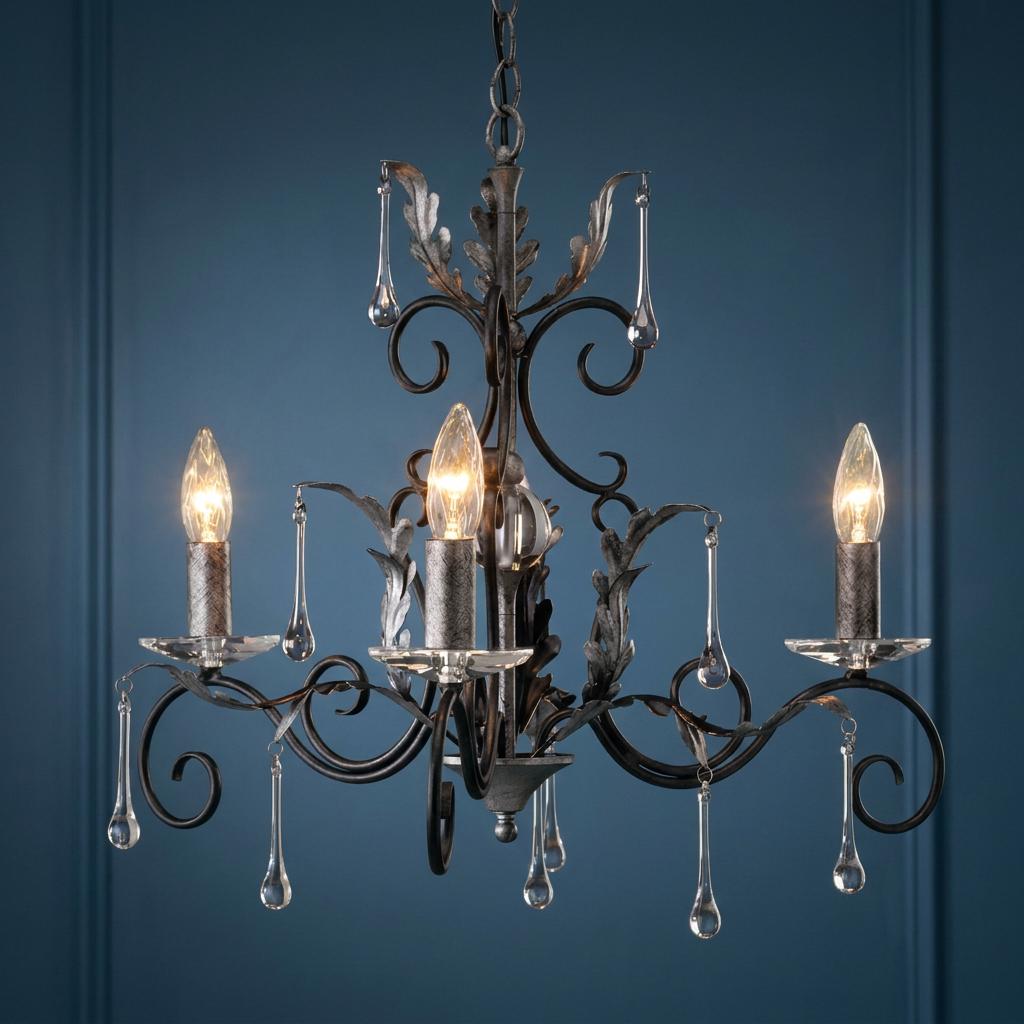 Three-light black and silver chandelier with oak leaf scrolls and glass droplets against a dark blue wall.