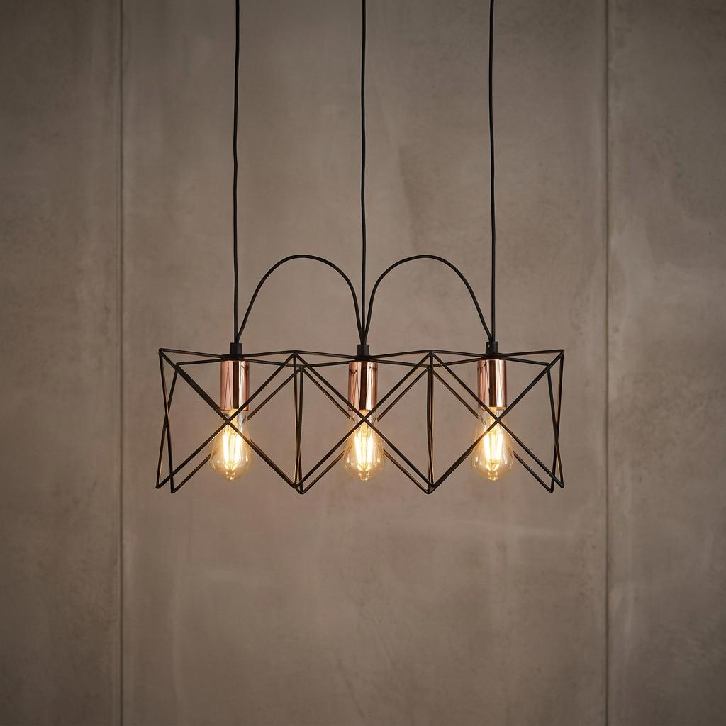 A black geometric wire cage pendant light with three glowing bulbs and copper accents against a grey textured wall.