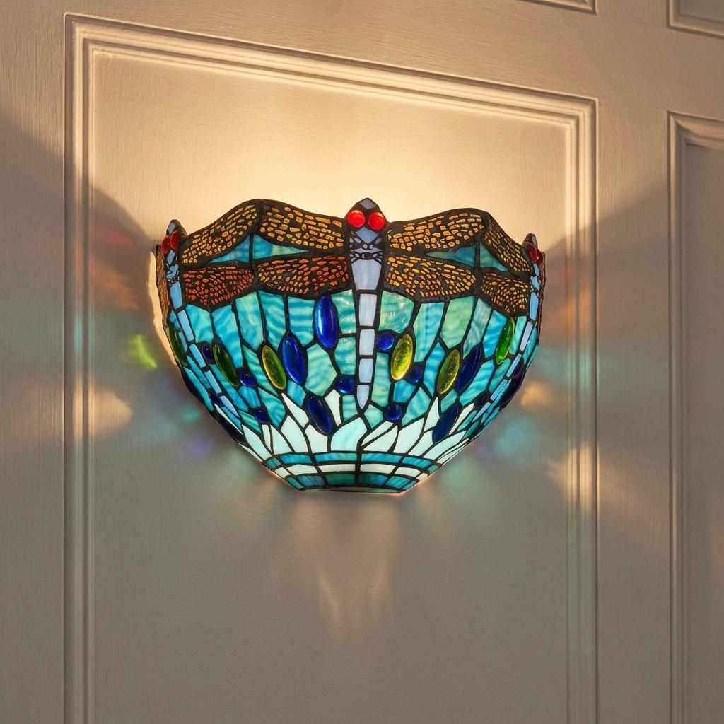 Vibrant aqua dragonfly Tiffany wall light with colorful stained glass mounted on a white paneled wall.
