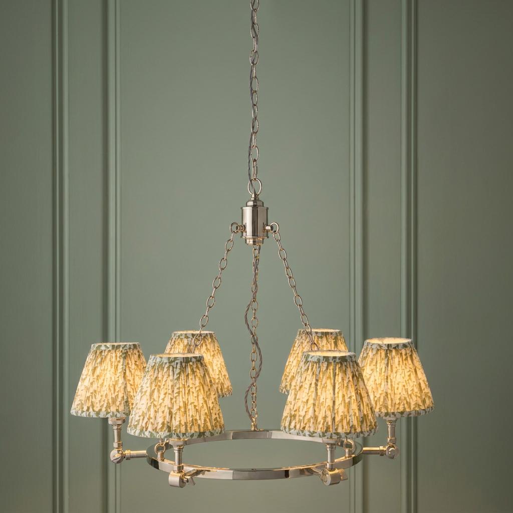 Five-light nickel ring chandelier with green leaf pattern fabric shades against a green paneled wall.