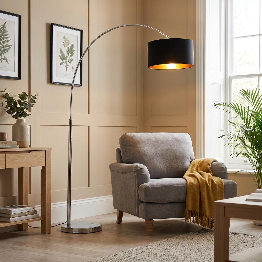 Arcs chrome floor lamp with a black and gold shade over a grey armchair in a neutral living room.