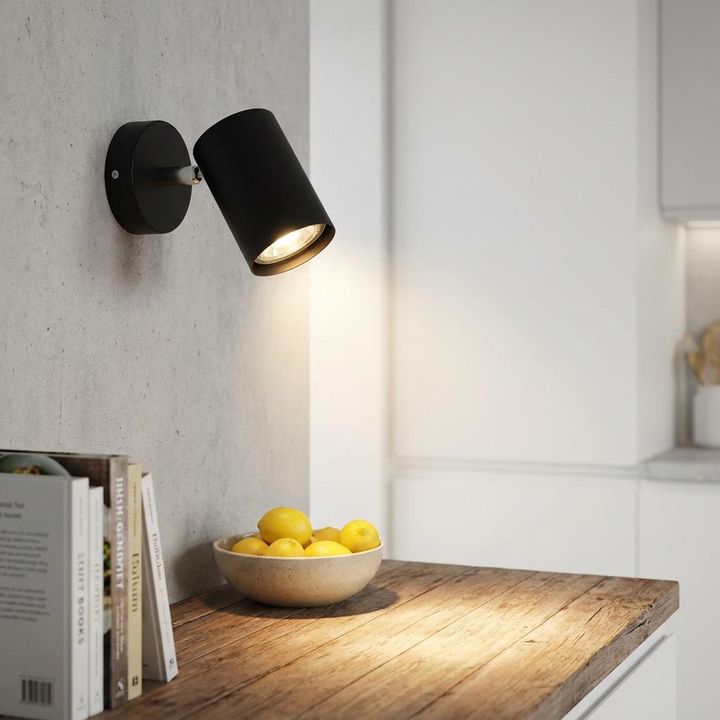 Matte black adjustable wall spotlight illuminating a wooden counter with a bowl of lemons in a modern kitchen.