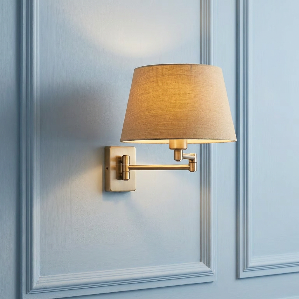 Armada Brass Swing Arm Wall Light with a beige fabric shade mounted on a light blue paneled wall.