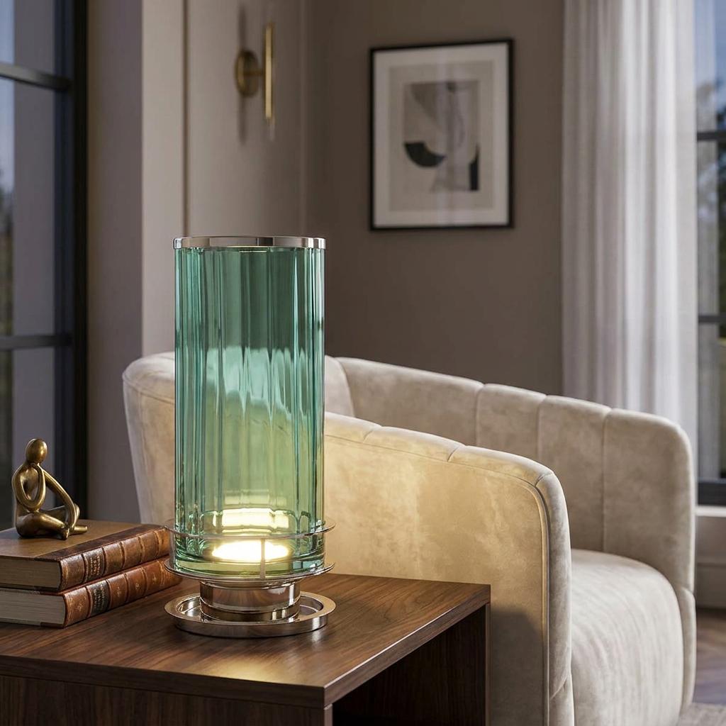 A ribbed green glass table lamp with a polished nickel base glows on a wooden side table next to an armchair.