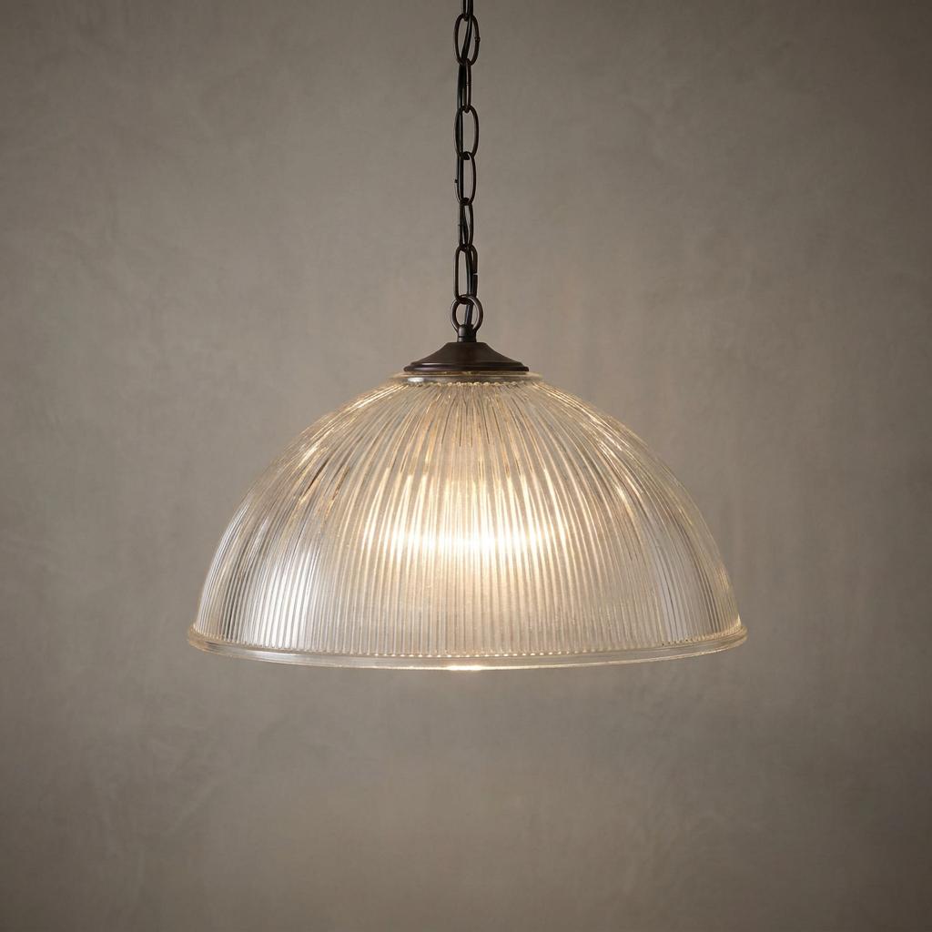 Art Deco large prismatic glass dome ceiling light with a dark bronze chain, illuminated against a textured wall.