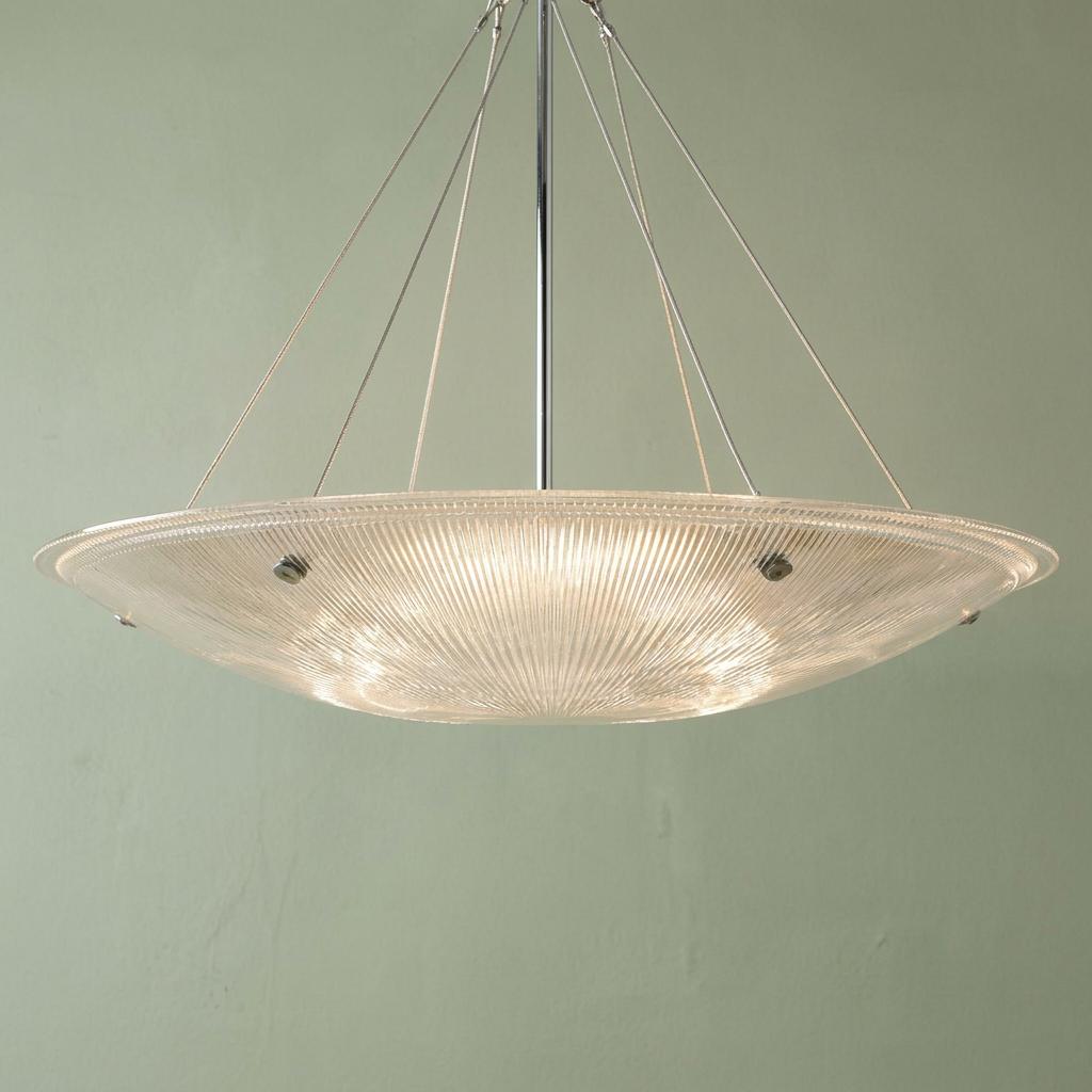 Art Deco prismatic glass bowl ceiling light suspended by cables against a pale green wall.
