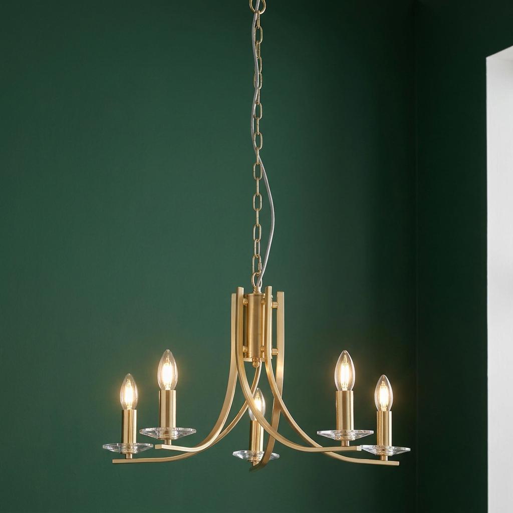 Satin brass Ascona 5-light pendant with curved arms and glass sconces hanging against a dark green wall.
