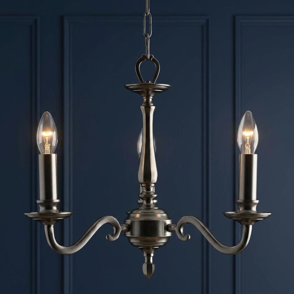 Aylesbury 3-light chandelier in an antique nickel finish with glowing candle bulbs against a dark blue paneled wall.