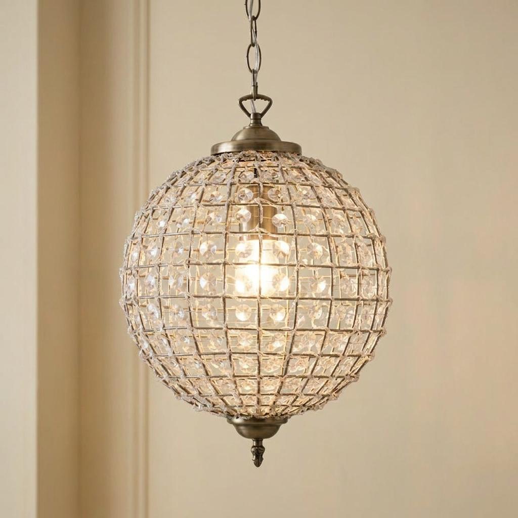 Spherical antique brass pendant light with a crystal-beaded grid shade hanging from a chain.