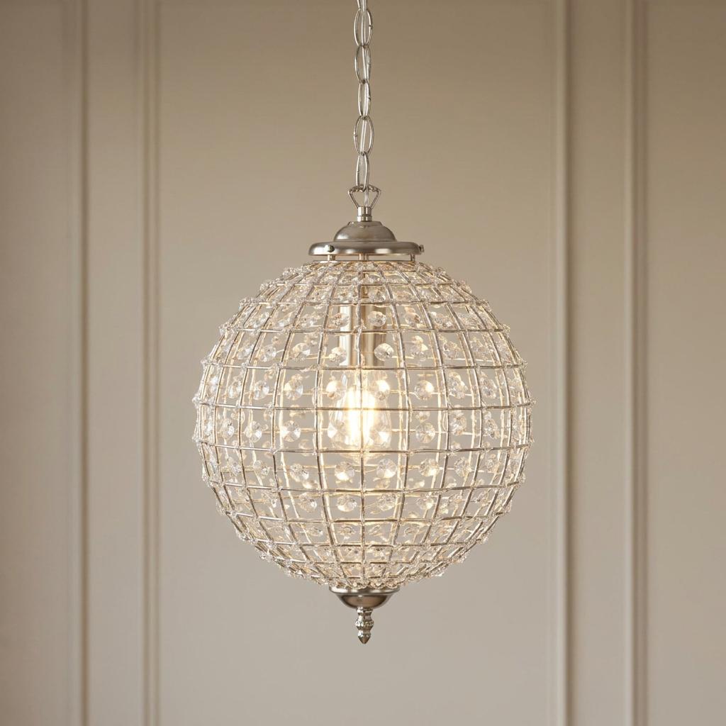 Spherical antique chrome pendant light with acrylic beads in a grid pattern, lit against a neutral paneled wall.