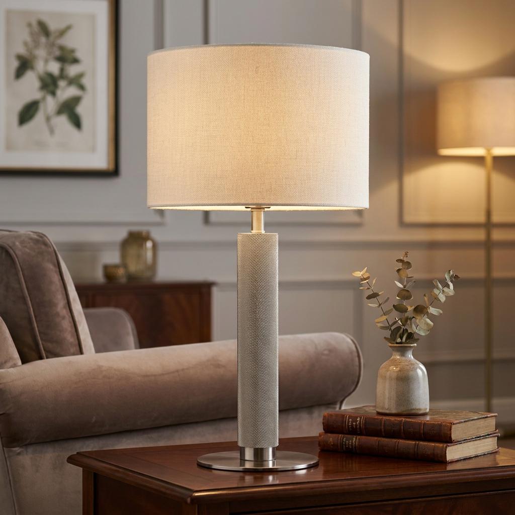 London Table Lamp with a knurled silver base and linen shade on a wooden side table in a living room.