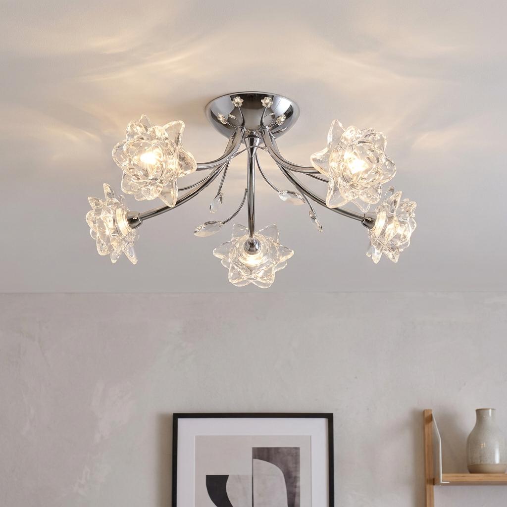 Five-light chrome semi-flush ceiling fixture with glass flower shades glowing in a modern room.