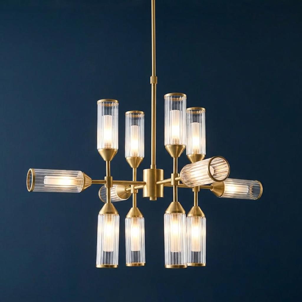 A 12-light brass pendant chandelier with ribbed glass shades, illuminated against a dark blue backdrop.