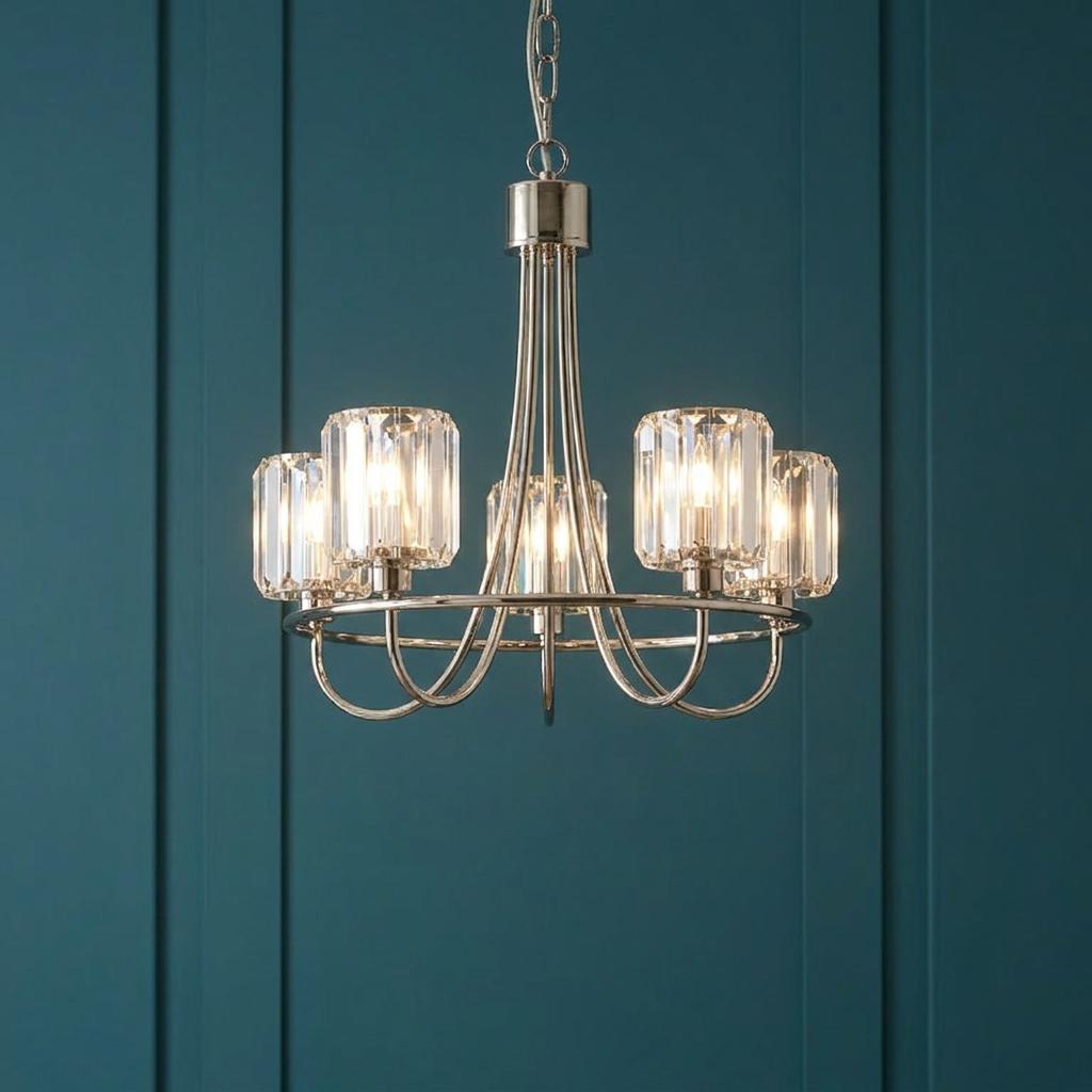 Berenice five-light nickel pendant with clear cut glass shades hanging against a dark blue paneled wall.