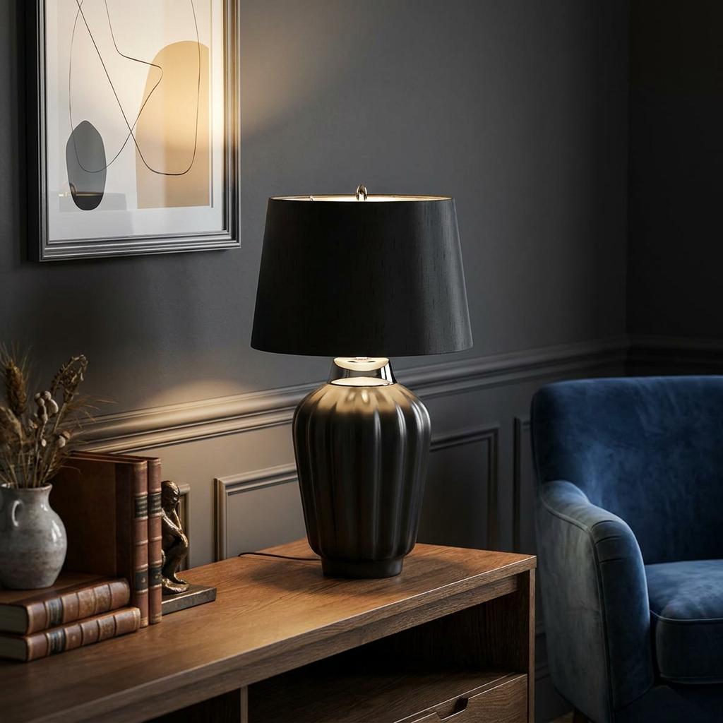 Bexley black fluted table lamp with a black drum shade on a wooden sideboard in a moody living room setting.