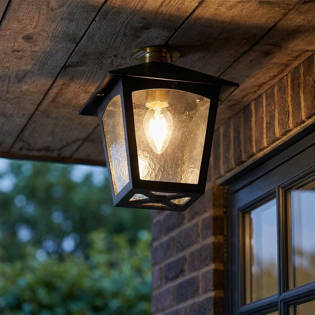 Black lantern outdoor flush mount light with textured glass, fixed to a wooden porch ceiling.