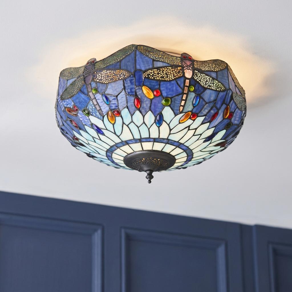 Blue dragonfly Tiffany flush ceiling light with stained glass jewels glowing against a white ceiling.