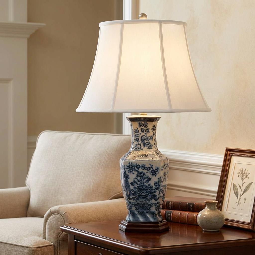 Blue and white ceramic table lamp with a floral hexagonal base and white flared shade on a wooden side table.