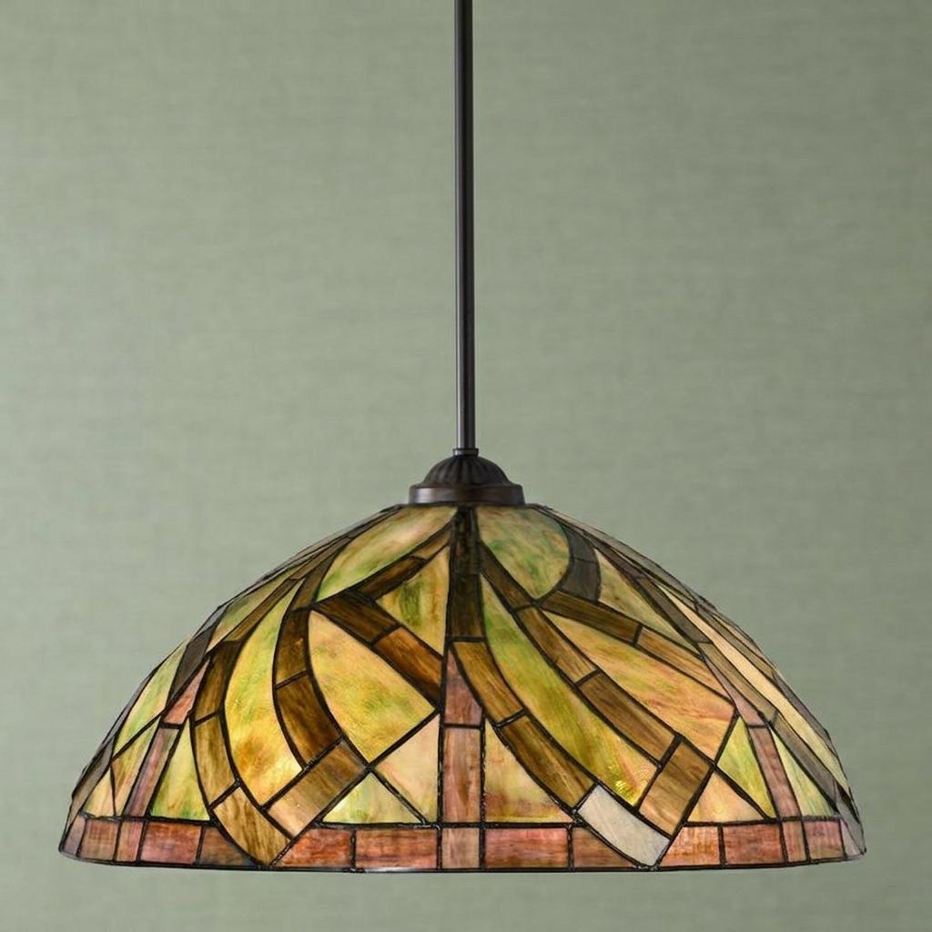 Tiffany pendant light with an abstract green and amber stained glass shade hanging against a pale green wall.