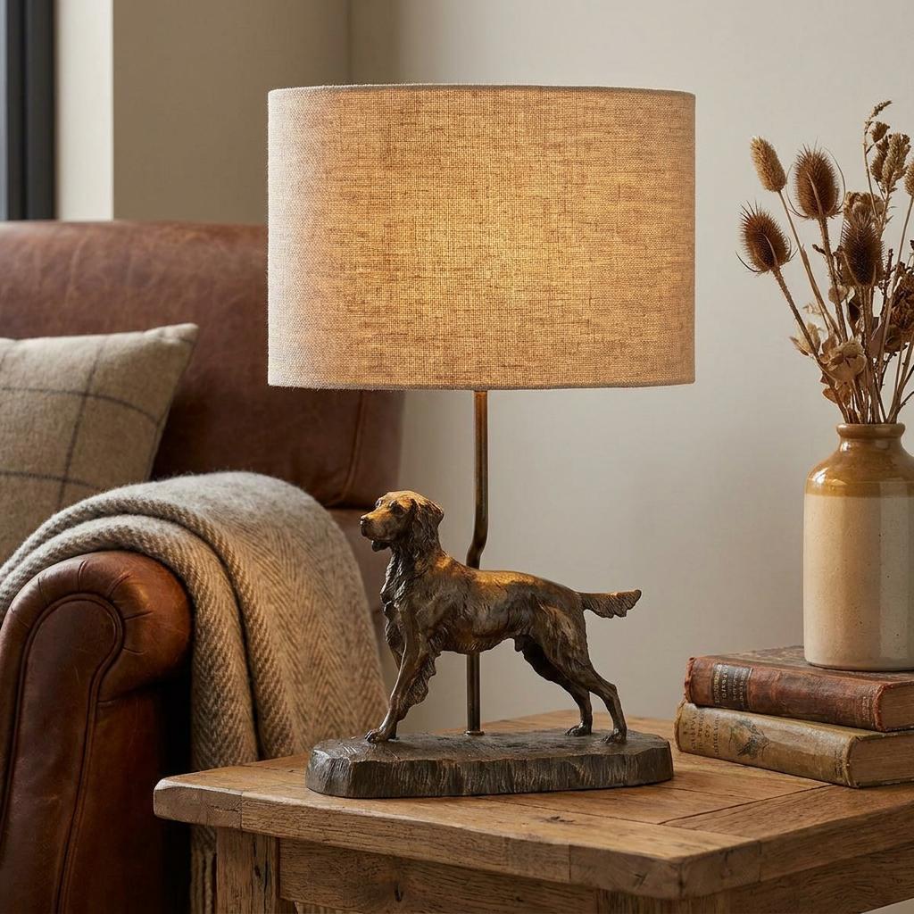 Bronze dog-themed table lamp with a natural oval shade on a wooden table next to a leather armchair.
