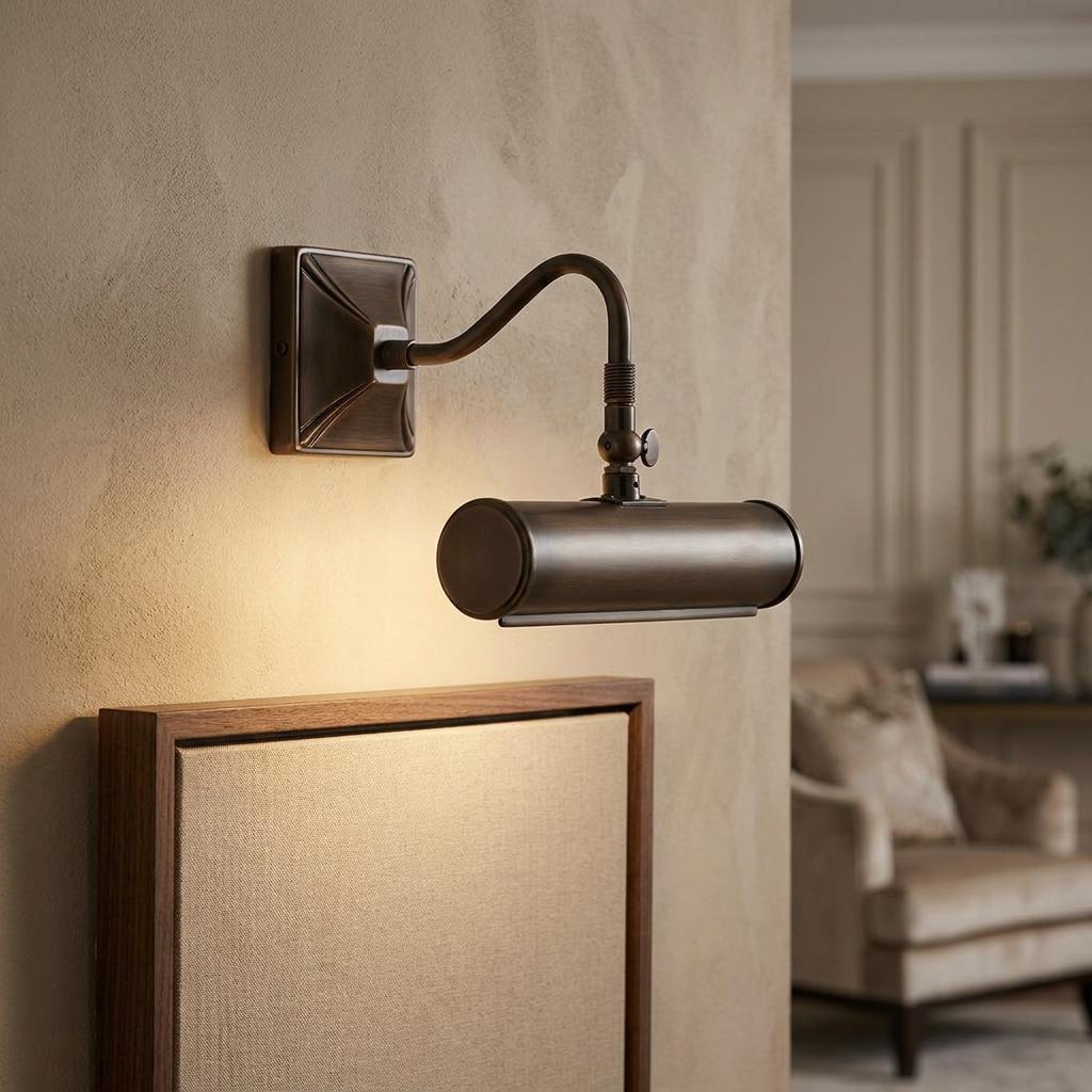 Wall-mounted brass picture light with a curved arm illuminating a framed canvas in a living room.