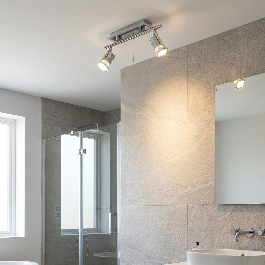 Chrome 2-light bathroom ceiling spotlight with pull cord mounted in a modern tiled bathroom.