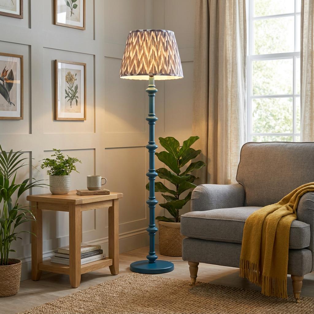 Blue carved floor lamp with a zigzag shade in a living room beside a grey armchair and wooden side table.