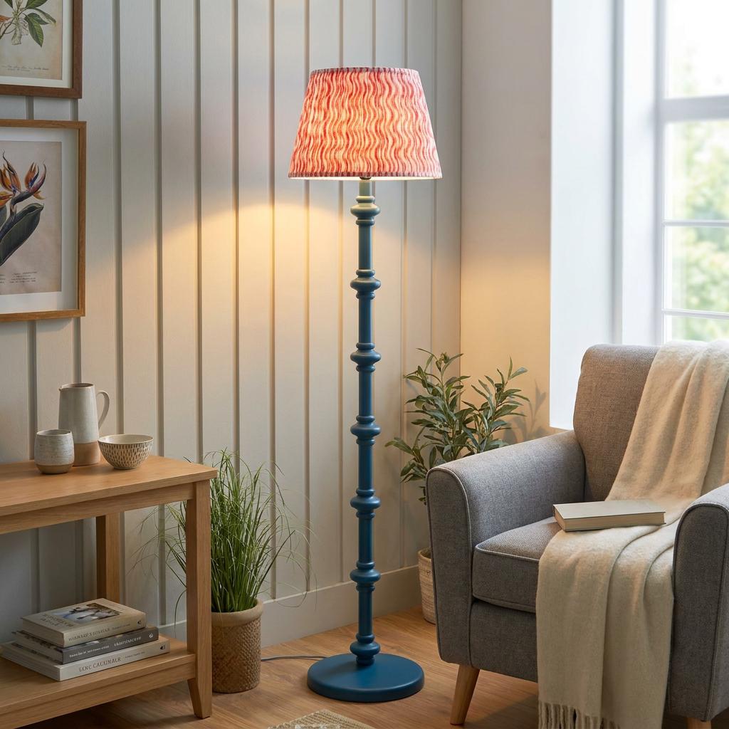 Carnaby Blue wooden floor lamp with a ripple coral pink shade lit in a cozy living room corner.