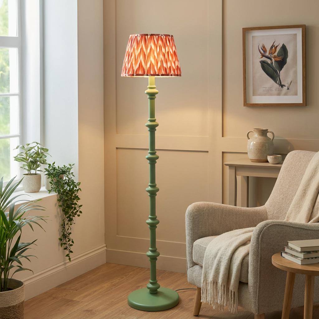 Carnaby green floor lamp with an apricot zigzag shade stands next to a beige armchair in a bright living room.