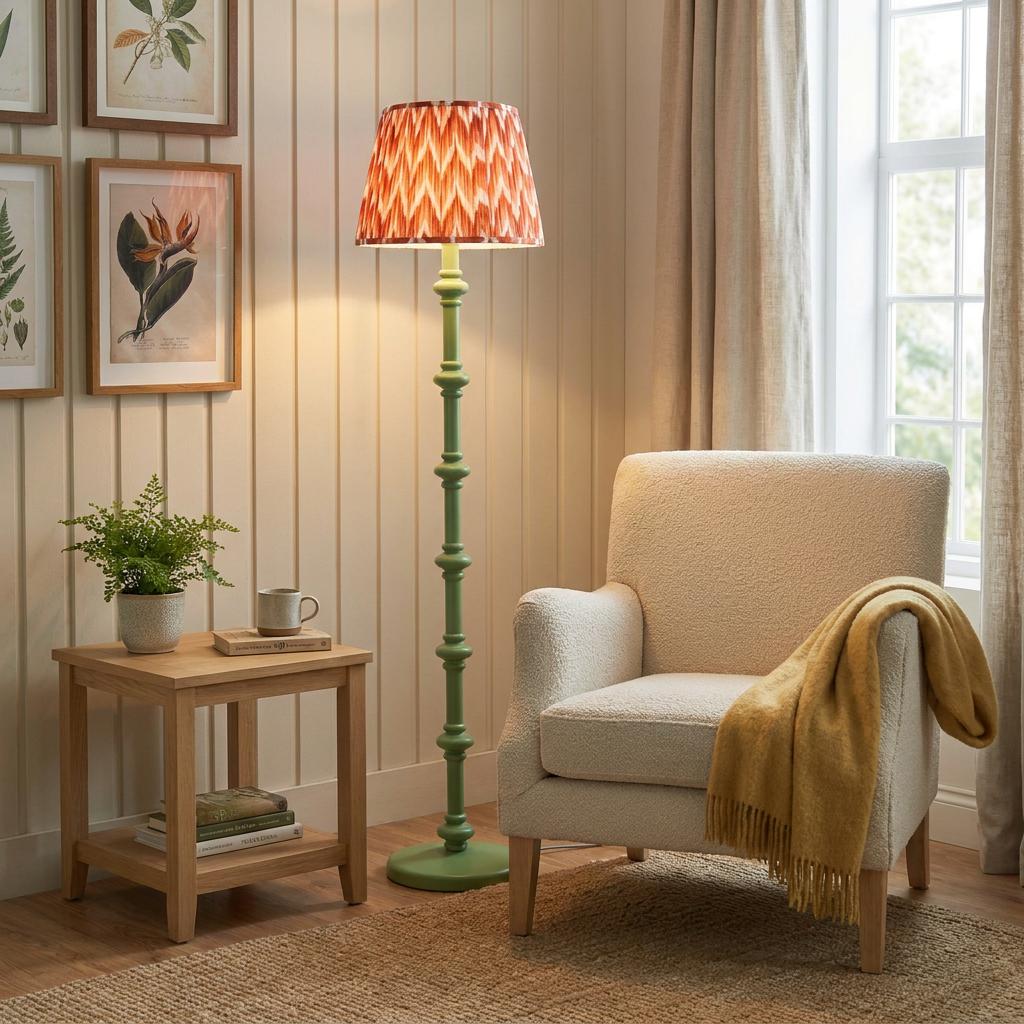 Carnaby green wooden floor lamp with orange zigzag ikat shade in a cozy living room nook by a white armchair.