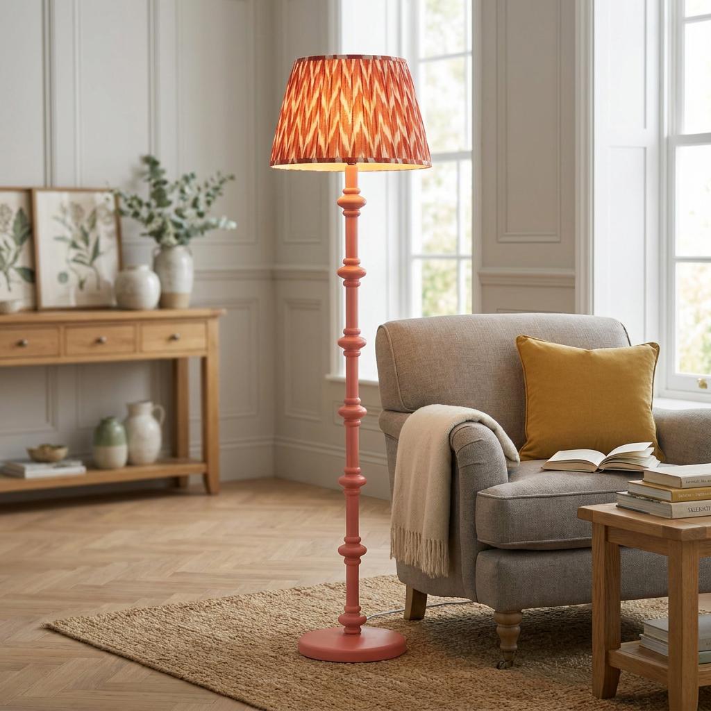 Pink Carnaby floor lamp with an apricot zigzag shade next to a grey armchair in a bright living room.