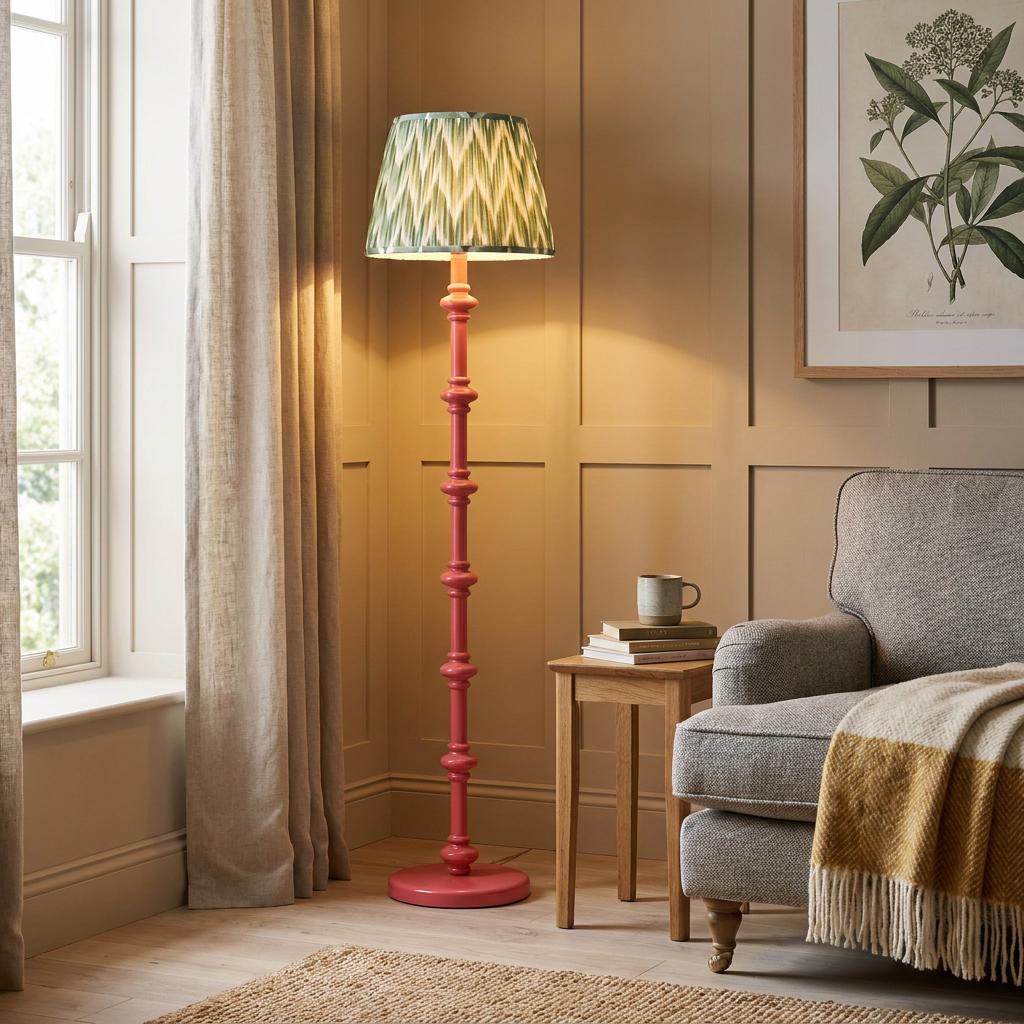 Pink bobbin floor lamp with a green zigzag shade in a cozy living room corner next to a grey armchair.