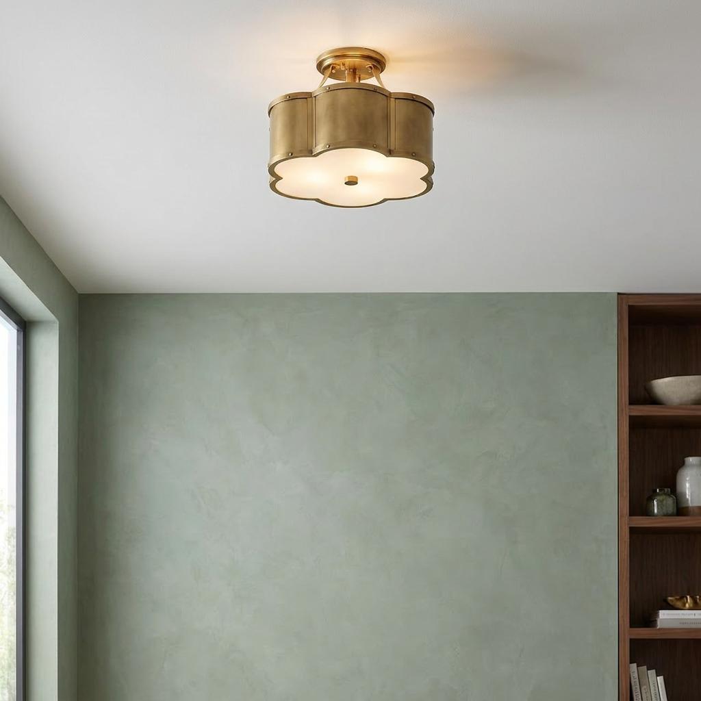 Scalloped brass semi-flush ceiling light with white diffuser mounted above a sage green wall.