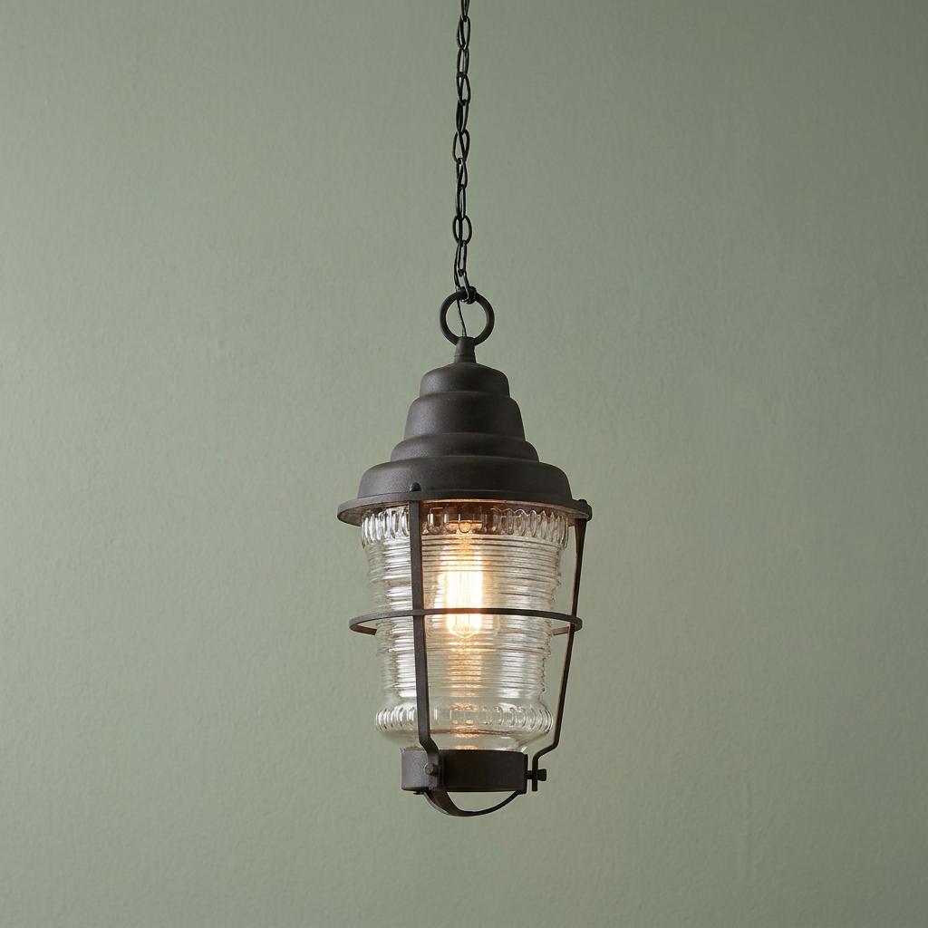 Nautical-style zinc outdoor chain lantern with a ribbed glass globe hanging against a green wall.