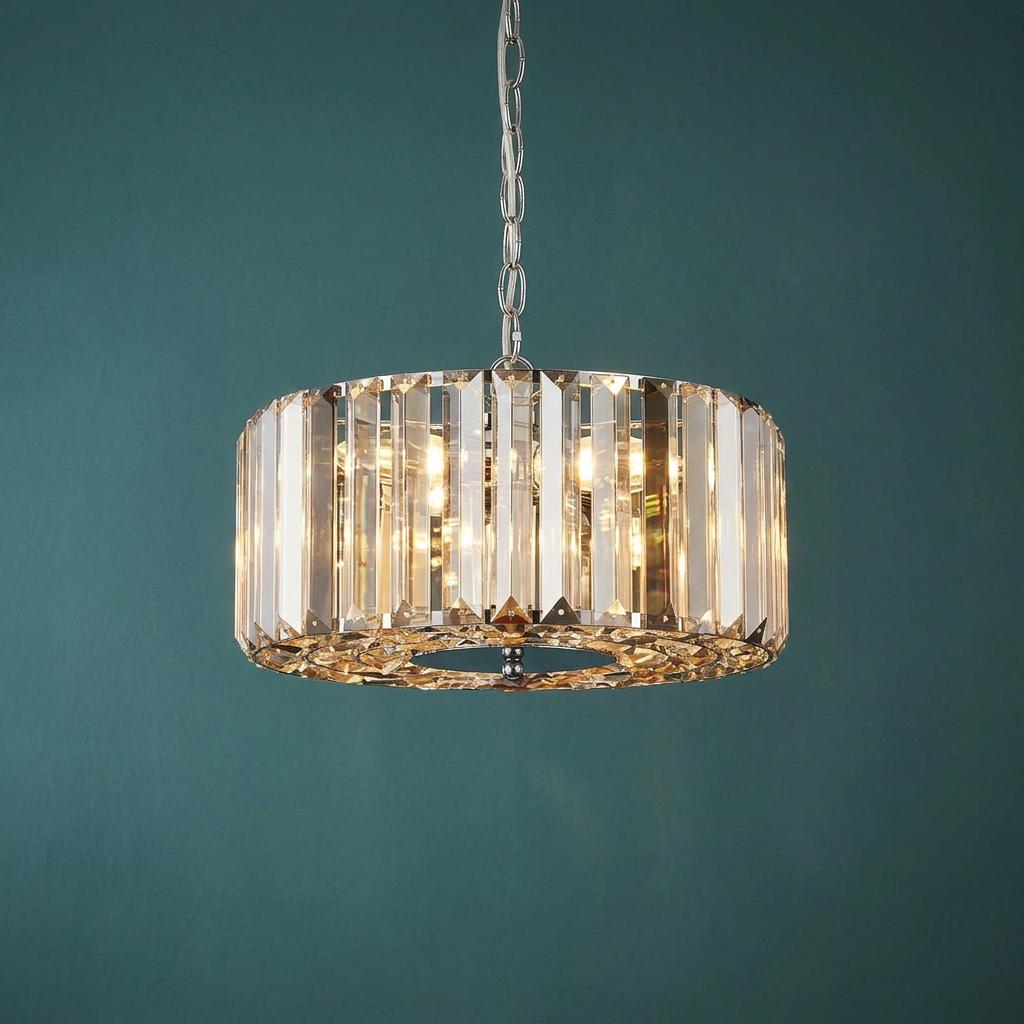 Chapeau 3 light chrome pendant with vertical glass crystals illuminated against a teal background.