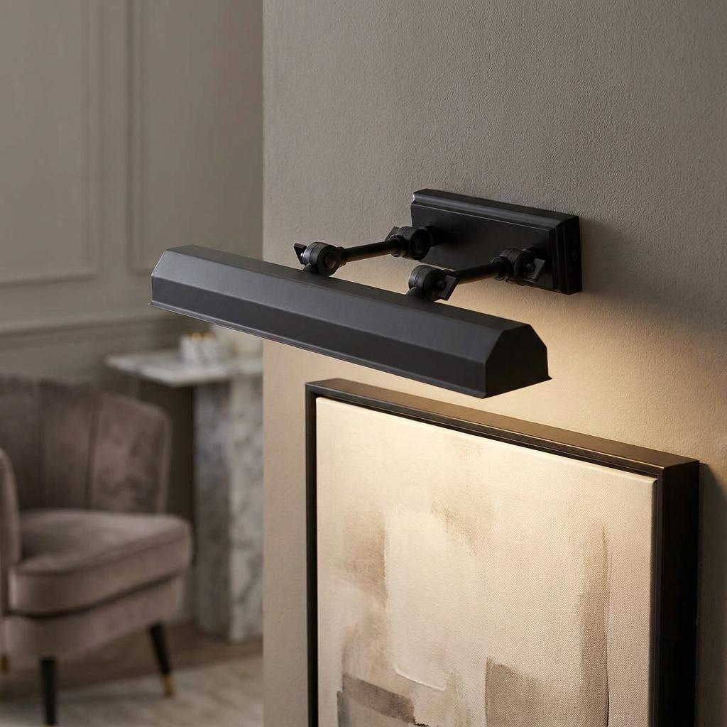 Black metal picture light mounted on a neutral wall, illuminating a framed abstract painting.