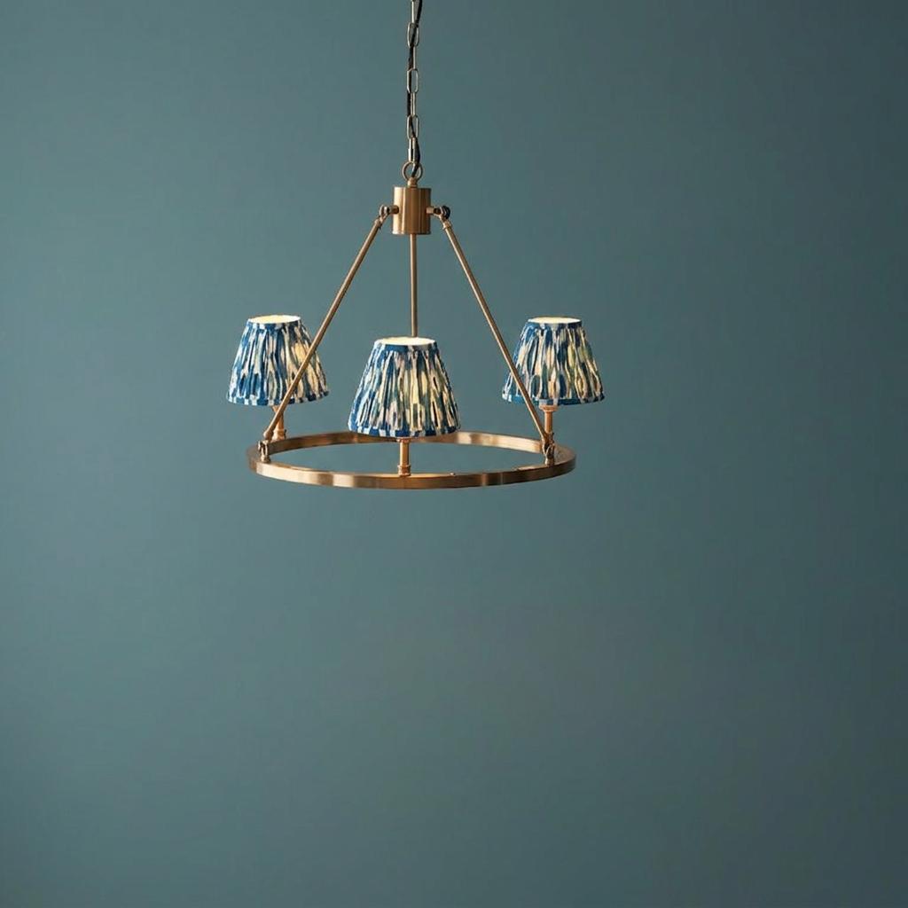 Chester brass ceiling pendant light with three blue ikat patterned shades against a teal-blue wall.