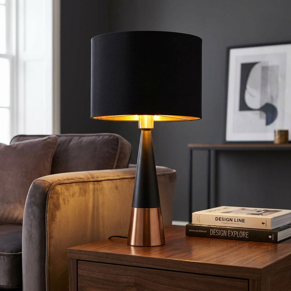 Chloe black and copper pyramid table lamp with black shade on a wooden side table next to a velvet sofa.