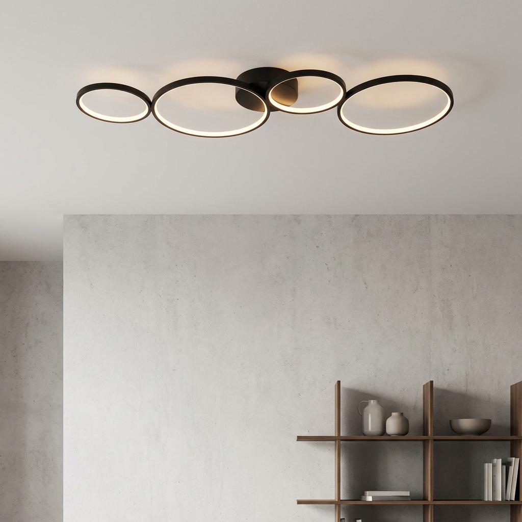 Modern black four-ring LED flush ceiling light mounted above a textured grey wall and wooden shelving unit.