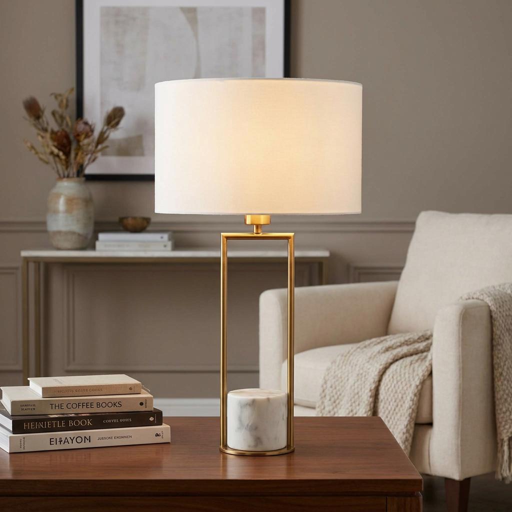 Claire Gold & White Marble Table Lamp with a white drum shade on a wooden side table in a cozy living room.