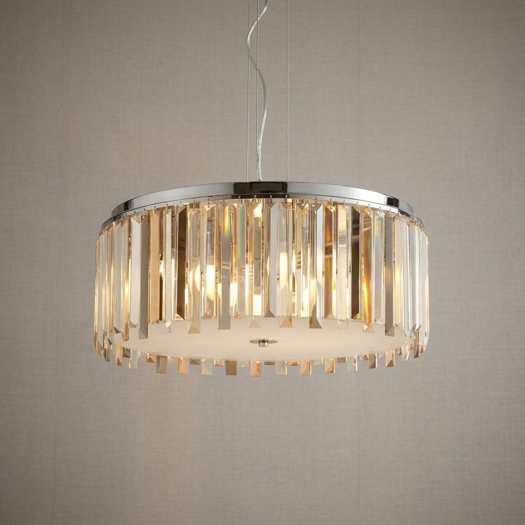 Chrome drum pendant light with shimmering crystal prism drops hanging against a neutral textured wall.