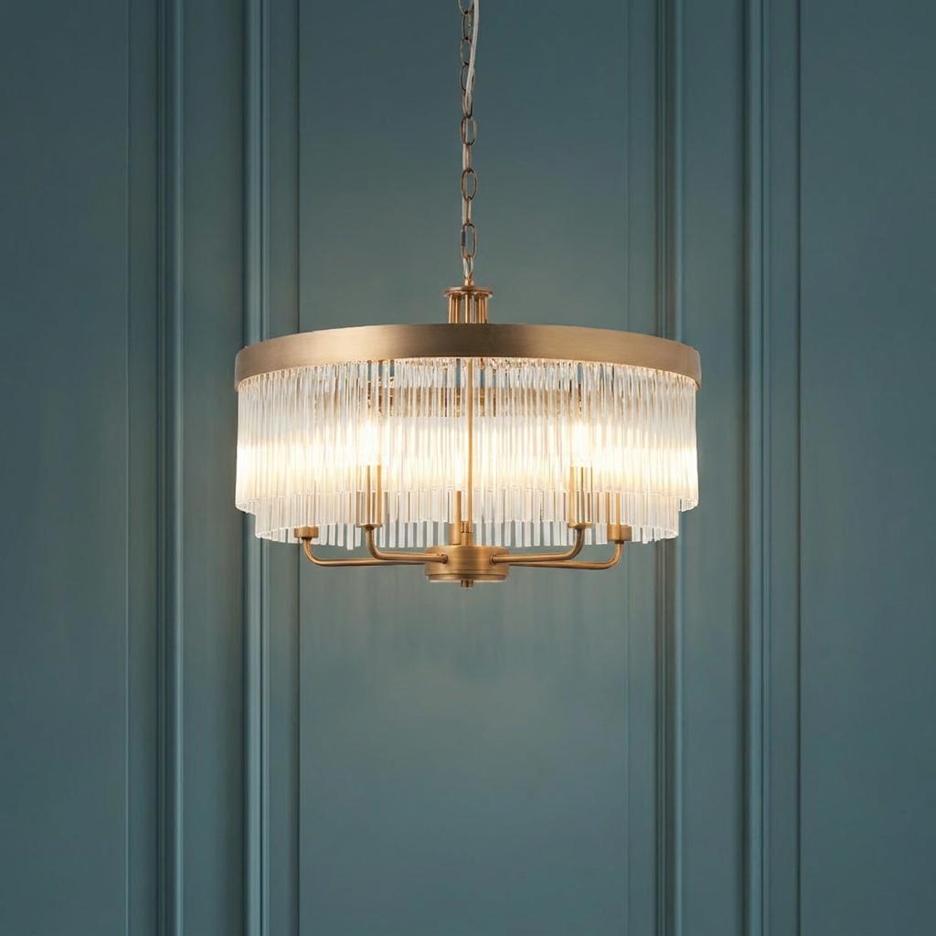 Clermont brass 5-light ceiling pendant with glass rods glowing against a teal paneled wall.