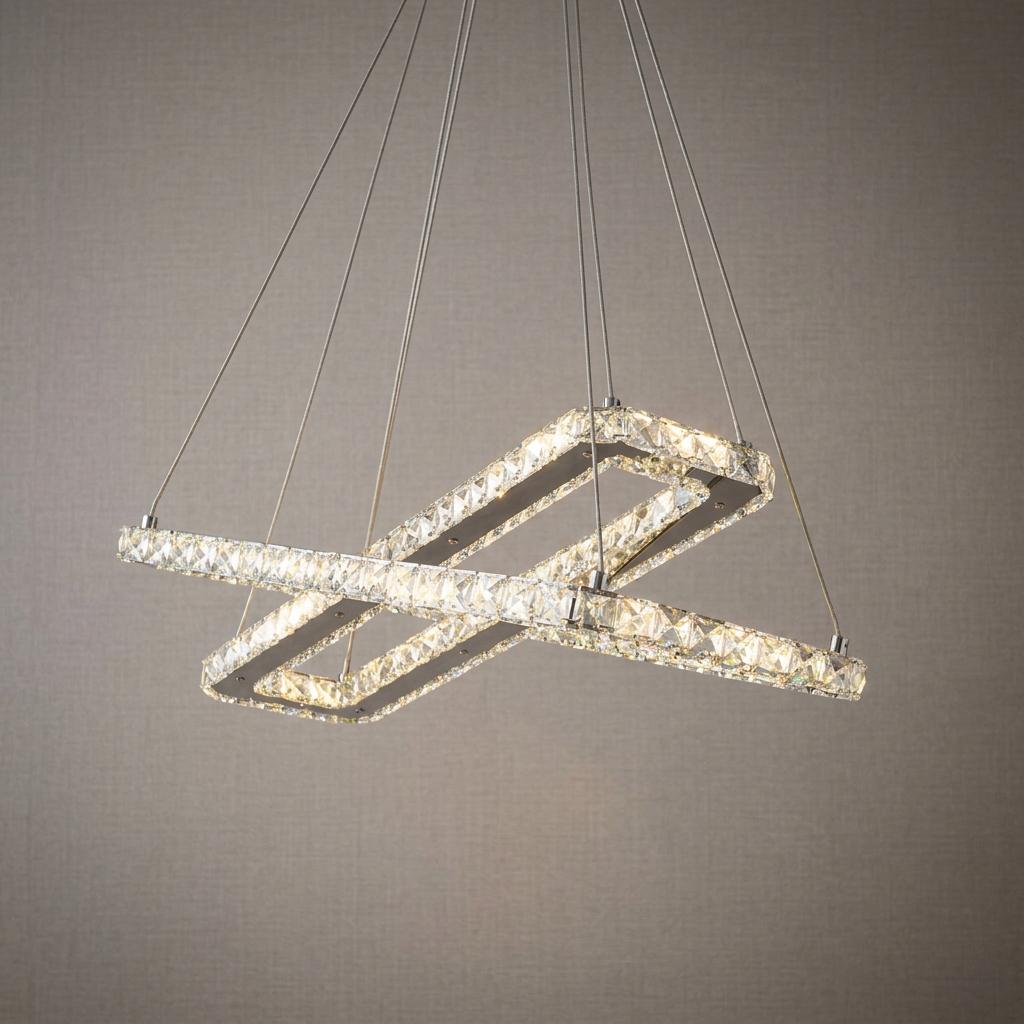 Intersecting chrome and crystal rectangular LED ceiling pendant hanging against a textured neutral wall.