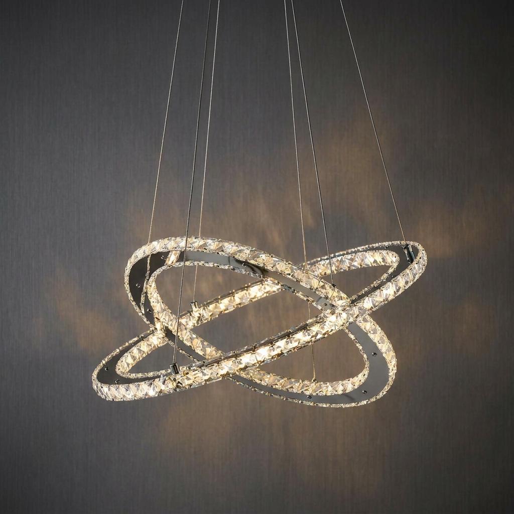 Intersecting chrome rings with glowing crystals suspended as a ceiling pendant light against a dark background.