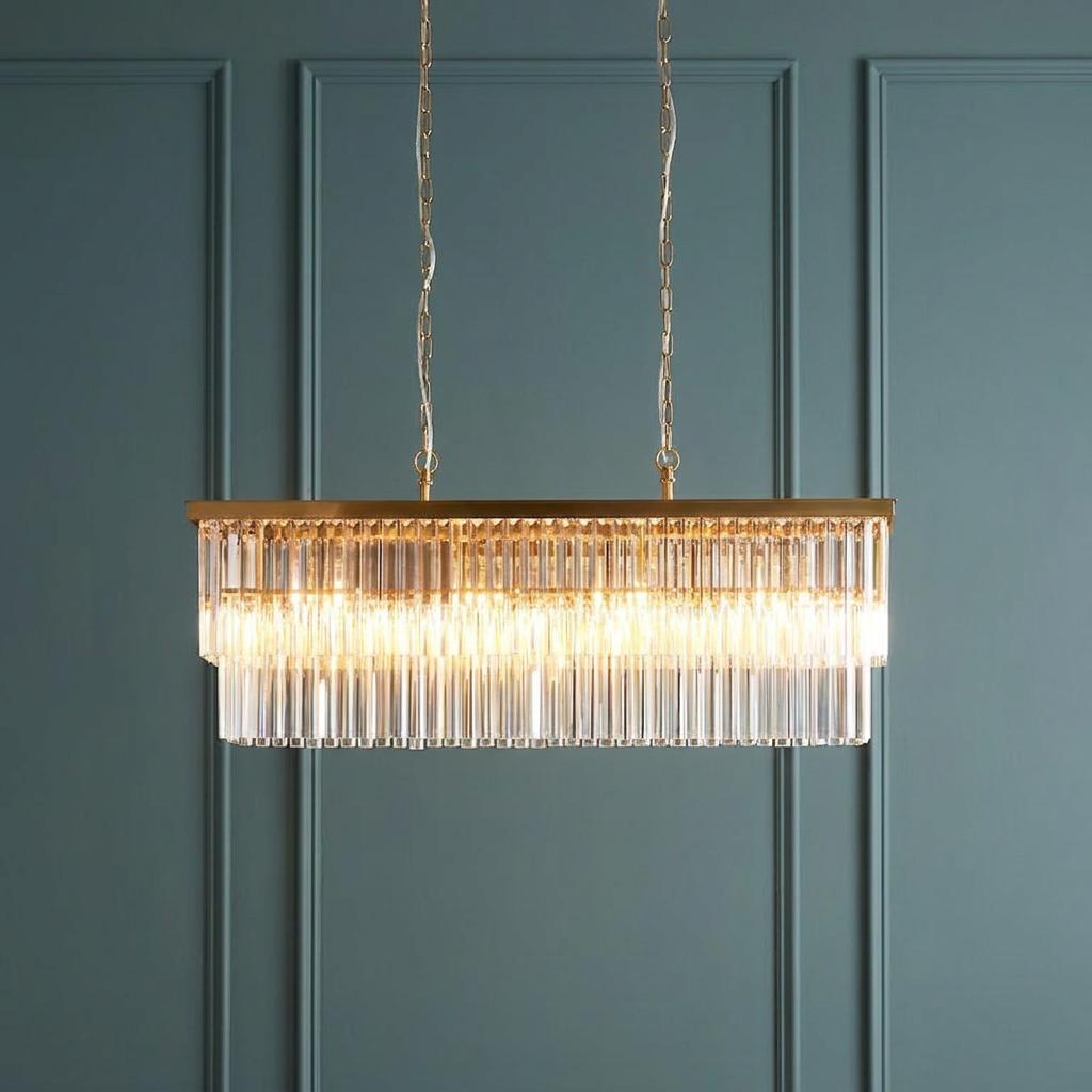 Conaston 4-light brass linear pendant with clear glass rods illuminated against a teal paneled wall.