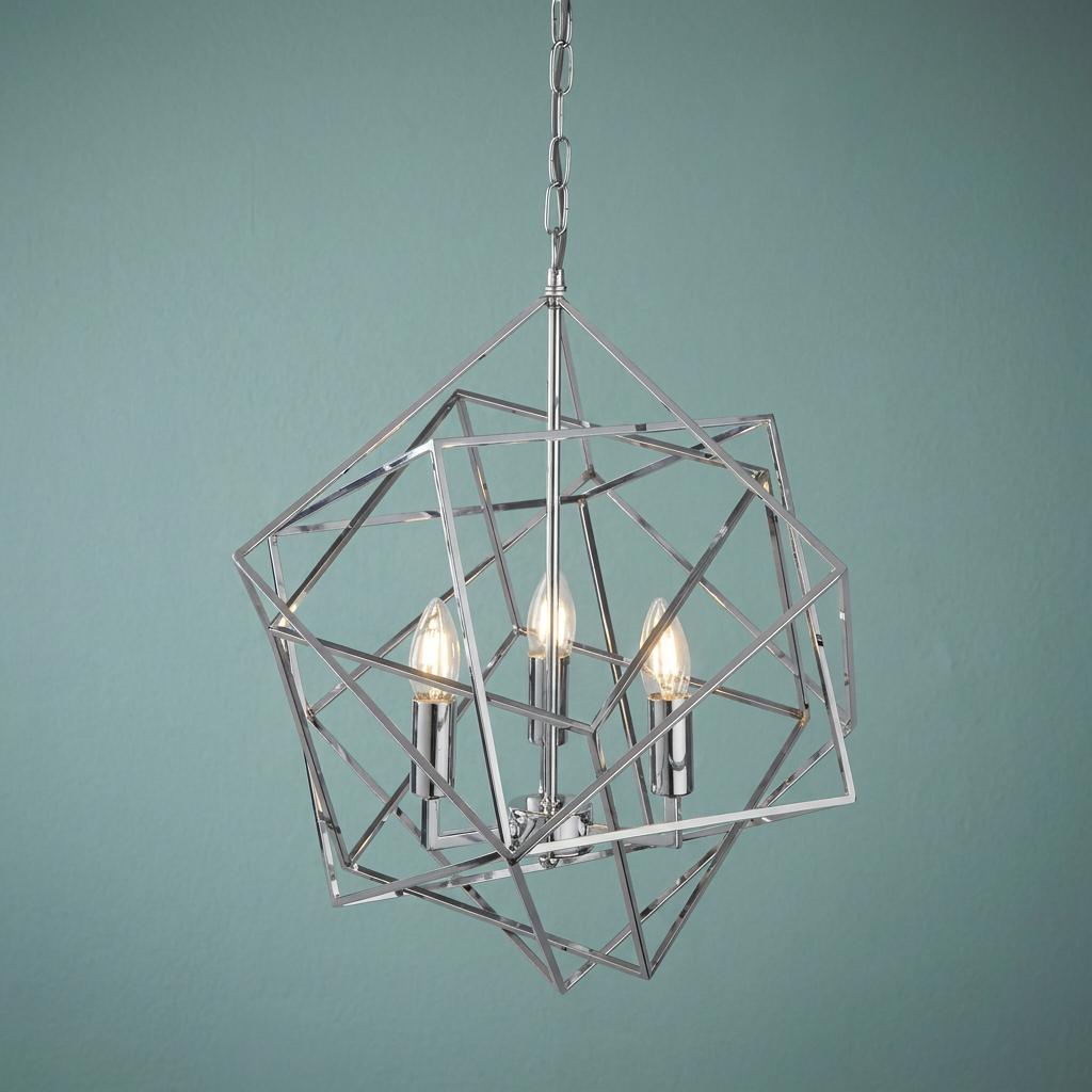 Three-light chrome geometric cube ceiling pendant with illuminated candle bulbs against a blue-green background.